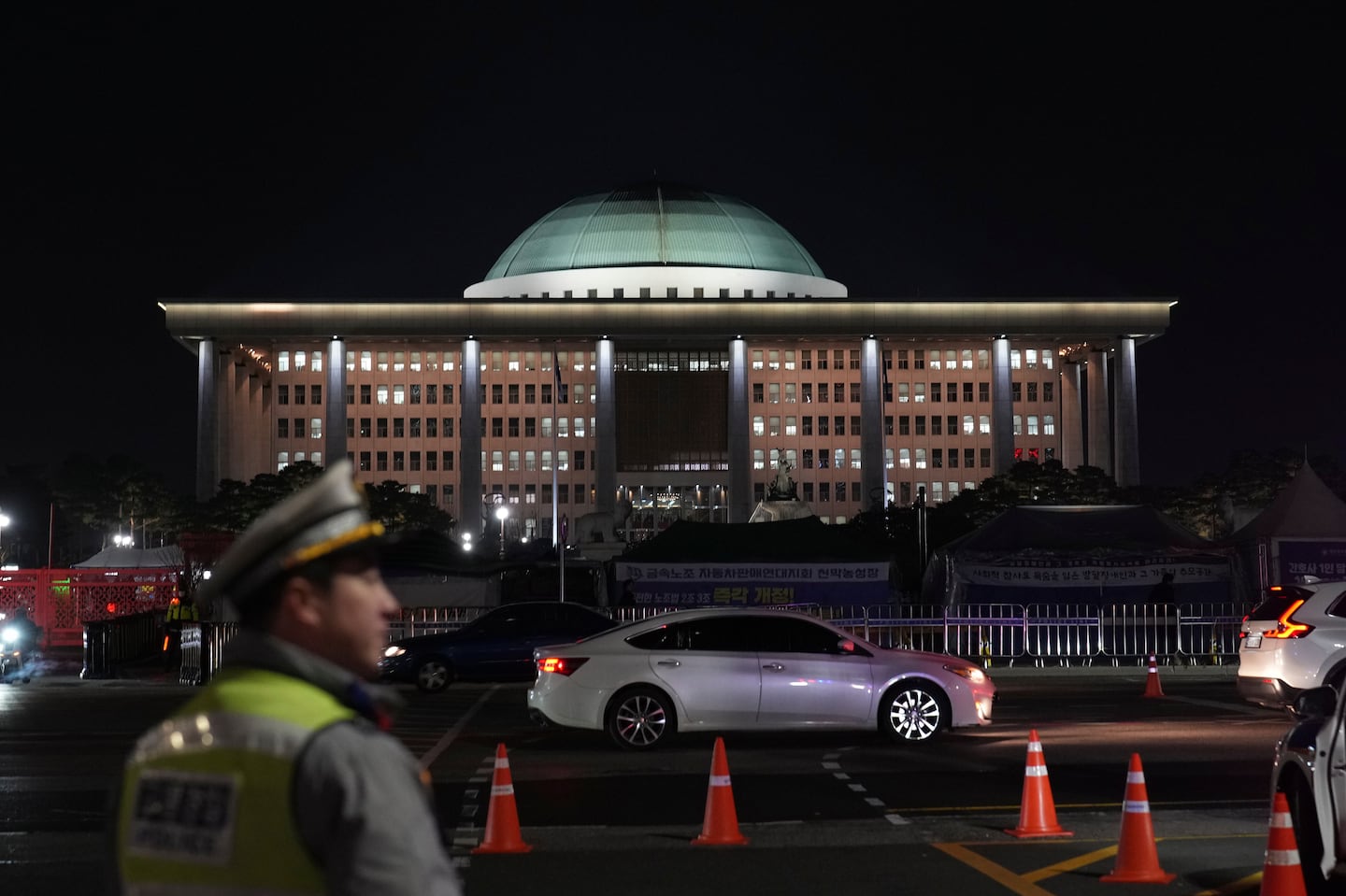 A traffic police office walks near the National Assembly as a rally demanding South Korean President Yoon Suk Yeol's impeachment is taking place, in Seoul, South Korea, Tuesday, Dec. 10, 2024.