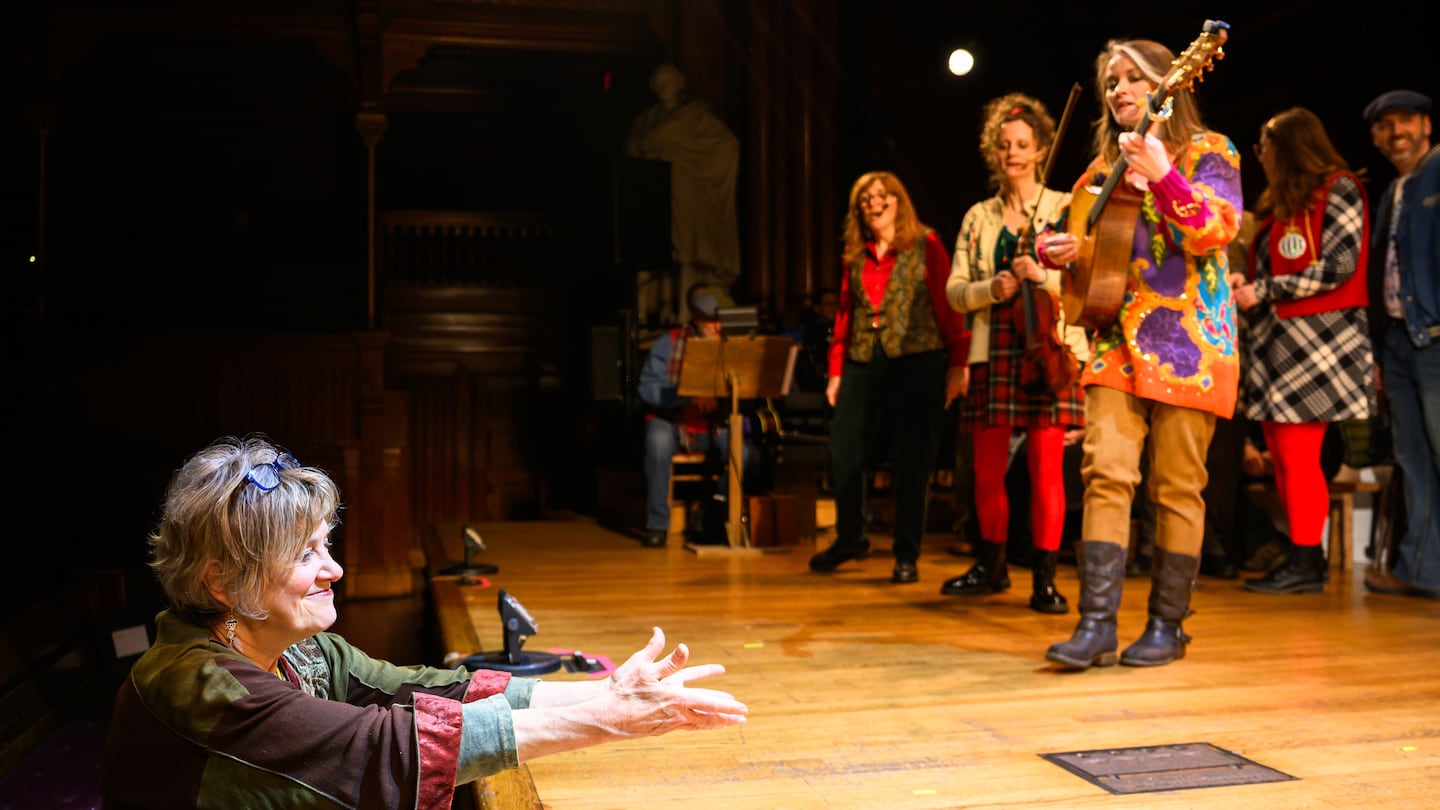 Director Debra Wise points to where performers should move at a dress rehearsal for the Midwinter Revels’ performance of “The Selkie Girl and the Seal Woman” in Sanders Theatre at Harvard University.