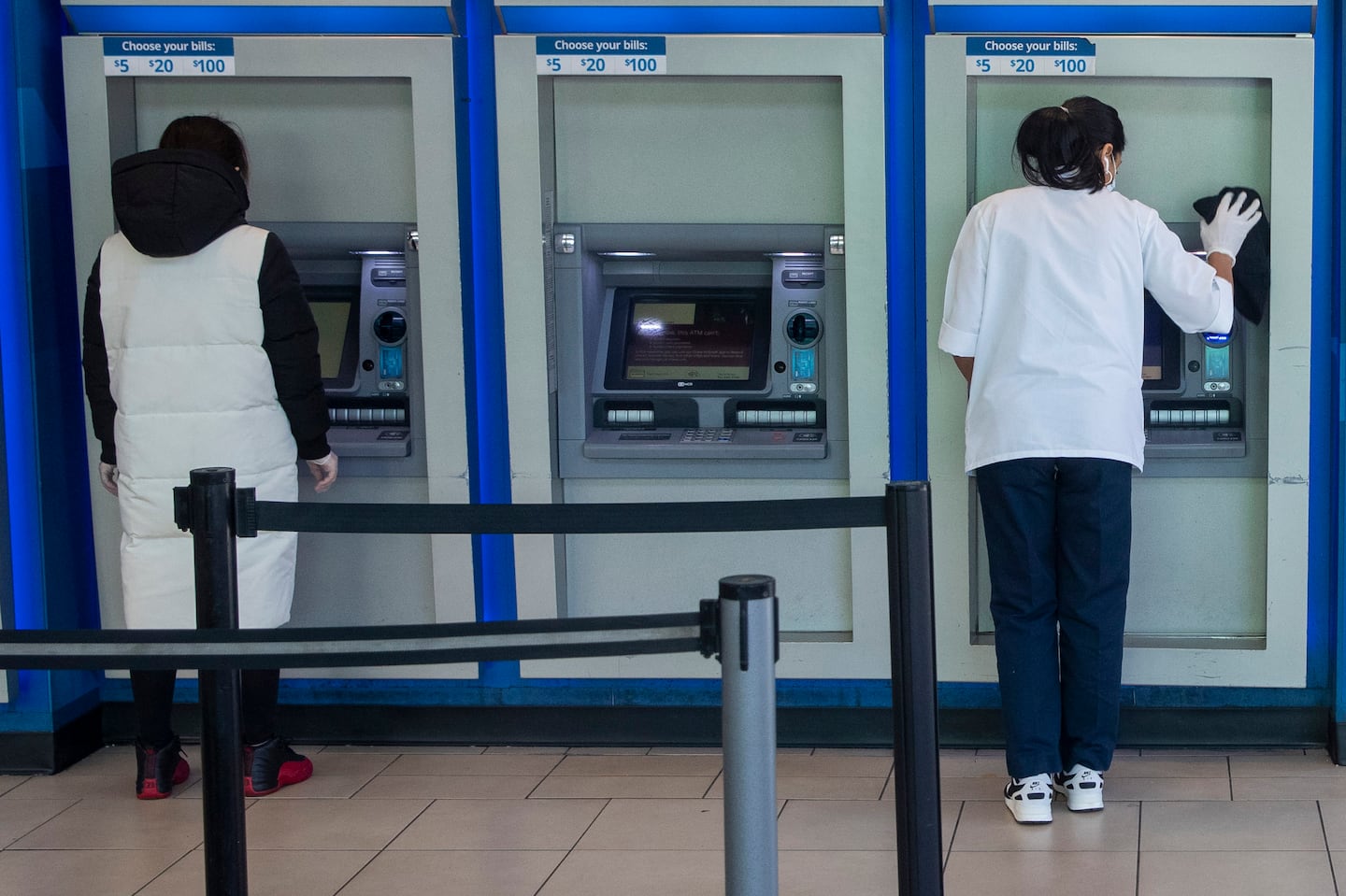 A customer makes a transaction at a bank of automatic teller machines in the Queens borough of New York on March 24, 2020.