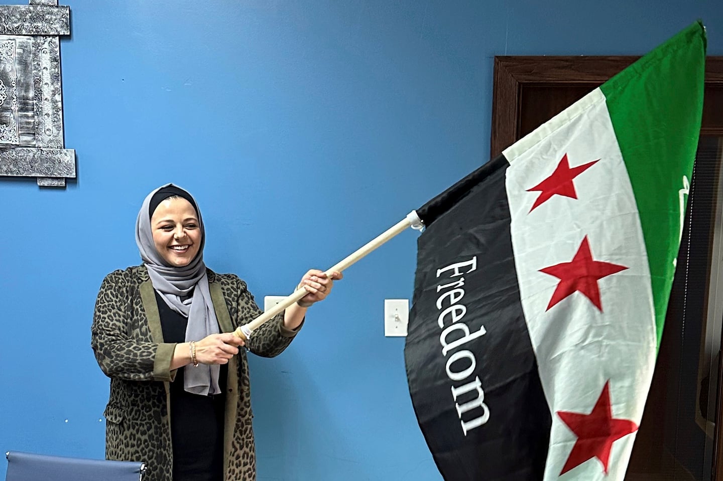 Rama Alhoussaini holds a Syrian flag in her Dearborn Heights, Mich. office, on Dec. 10.