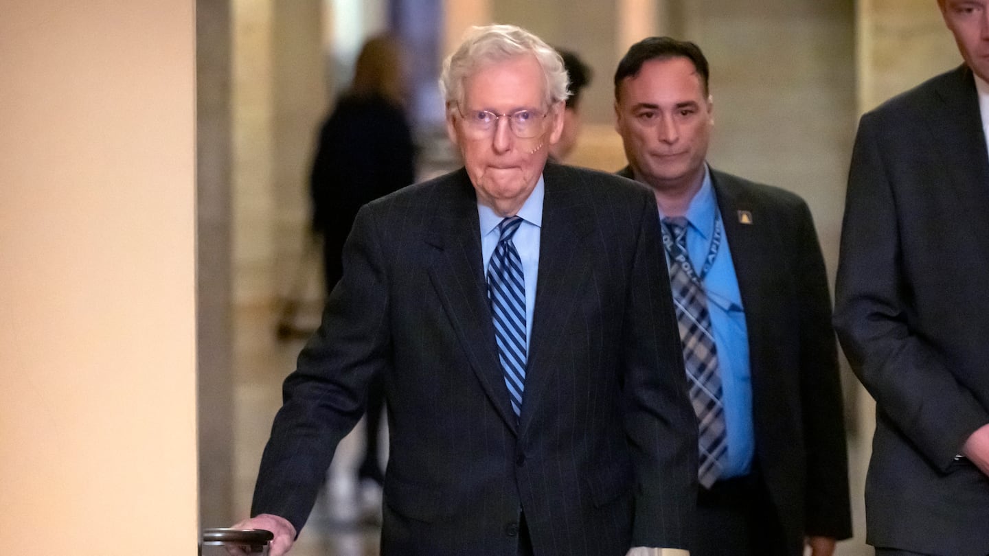 Senate Minority Leader Mitch McConnell of Ky., left, wears a bandage on his face and wrist as he walks to cast a vote on the Senate floor after falling during a luncheon on Capitol Hill.