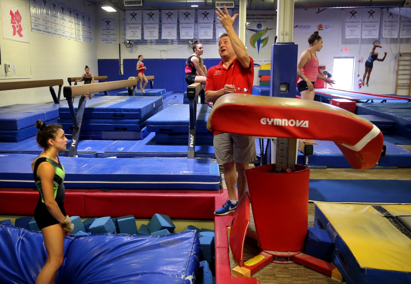 Coach Mihai Brestyan, center, instructs Sophia Voss, left, during her vault exercise at Brestyan's American Gymnastics Club in Burlington, Mass. in July 2021.