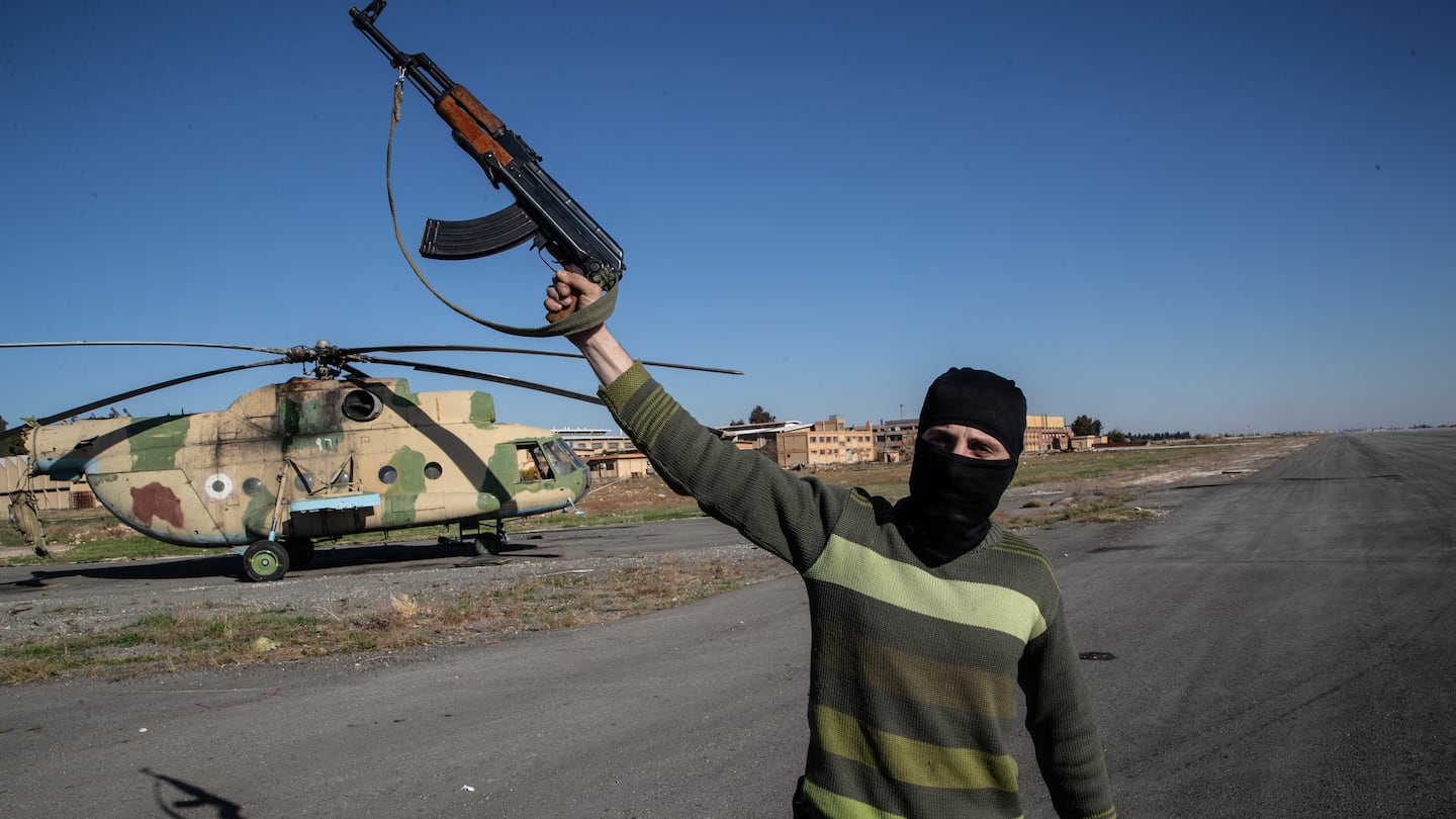 A Syrian opposition fighter gestured with his AK-47 in front of an abandoned Syrian army helicopter at the Aleppo airport on Saturday.