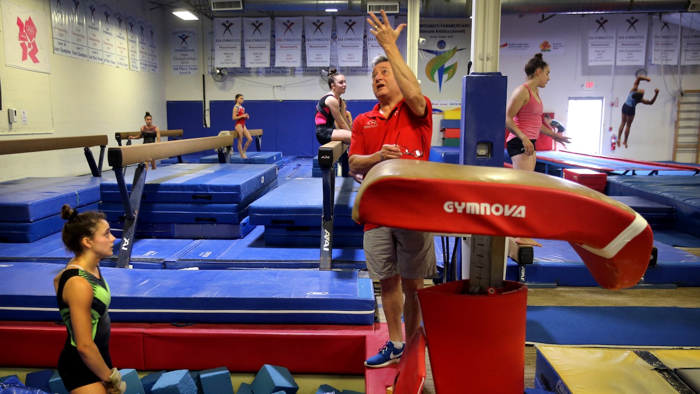 Coach Mihai Brestyan, center, instructs Sophia Voss, left, during her vault exercise at Brestyan's American Gymnastics Club in Burlington, Mass. in July 2021.