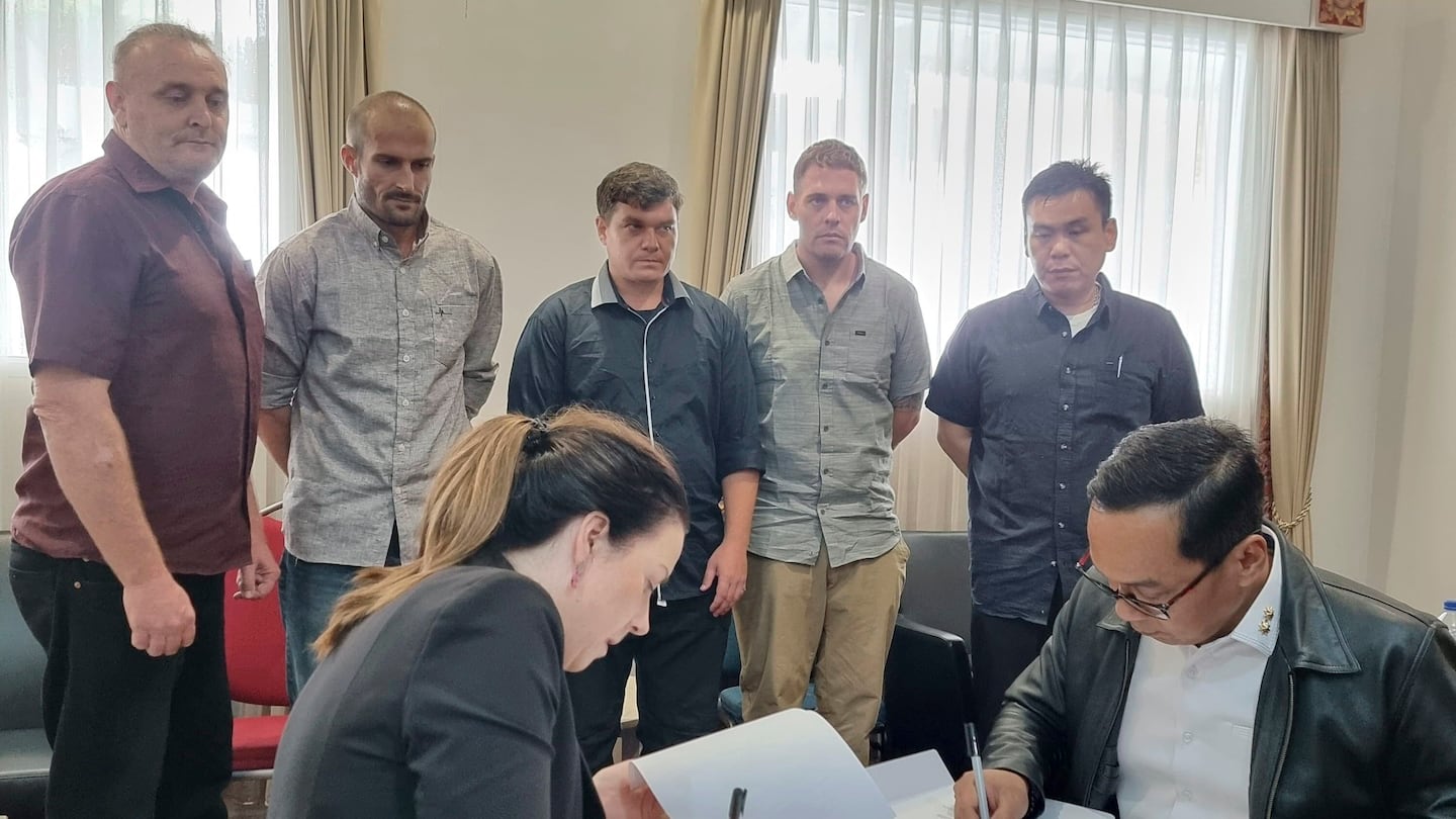 In this photo, Indonesian and Australian officials sign handover documents as five Australians who have spent almost 20 years in Indonesian prisons for heroin trafficking look on, prior to their return to Australia, in Bali, Indonesia, Sunday, Dec. 15, 2024.