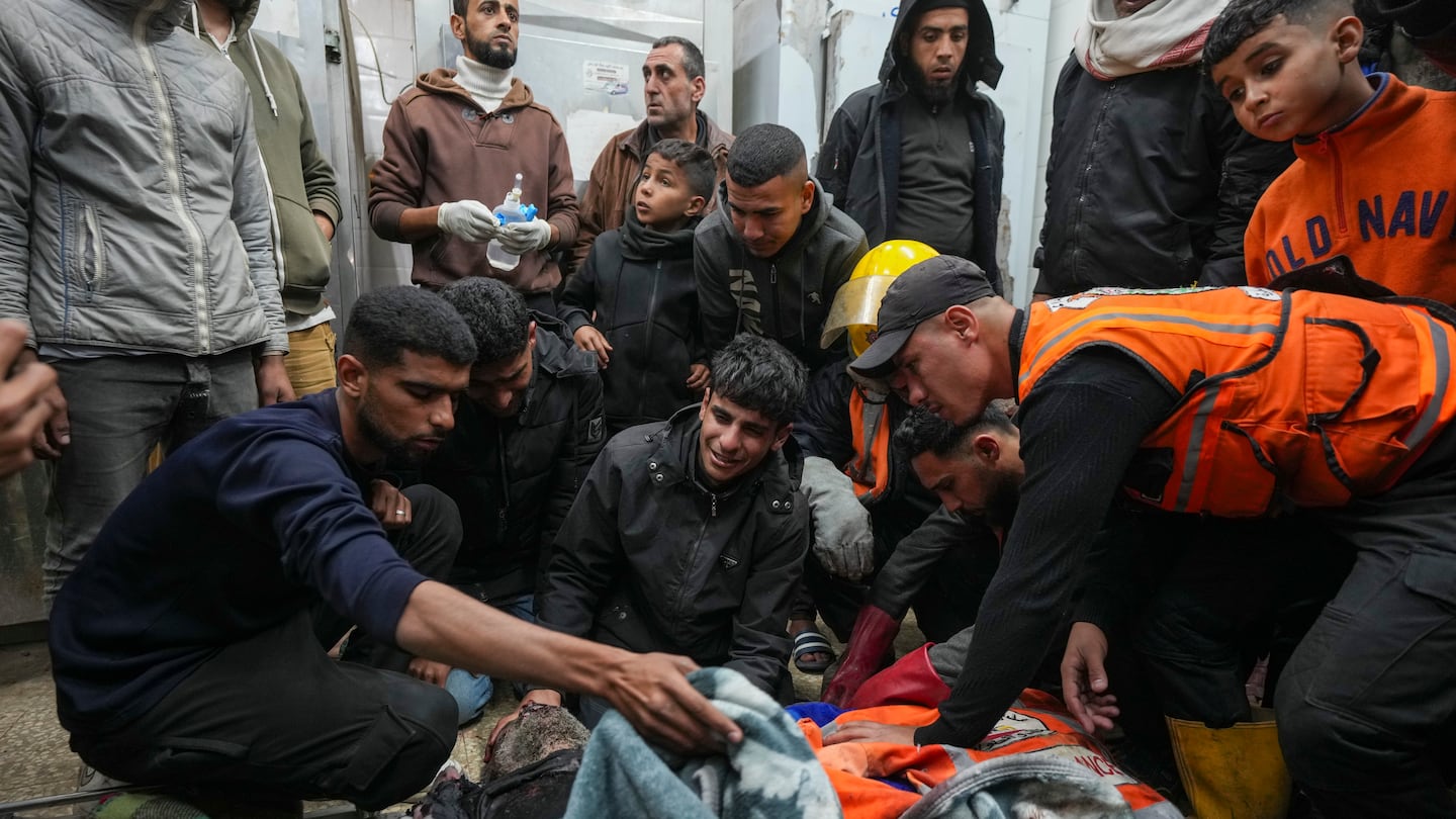 Palestinians mourn over the bodies of civil defense workers victims of an Israeli army strike in the Nuseirat camp, at the Al-Aqsa Martyrs hospital in Deir al-Balah, central Gaza Strip, on Dec. 16.