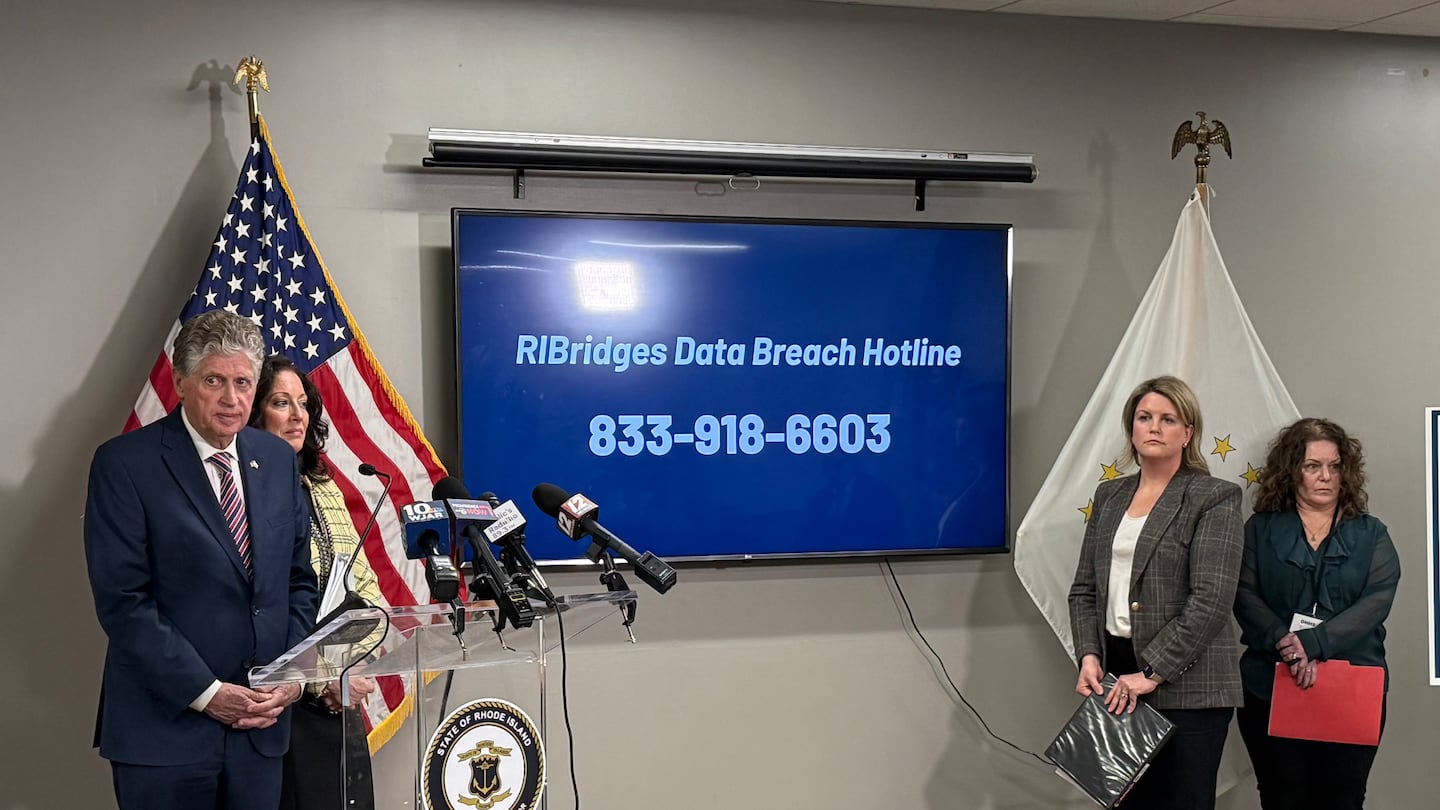 State officials including Governor Dan McKee display a hotline number set up over the weekend for people to call with questions after the cyberattack on Rhode Island's benefits system.