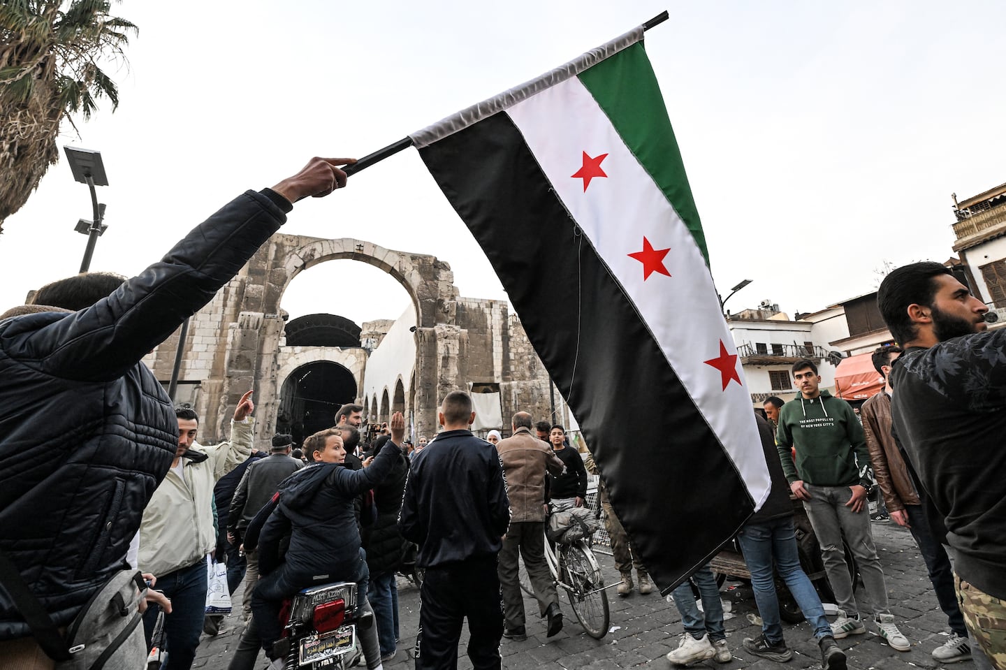 A man holds a flag of the Syrian opposition near the entrance of the Hamidiyah covered market in the old part of Damascus on Dec. 10.