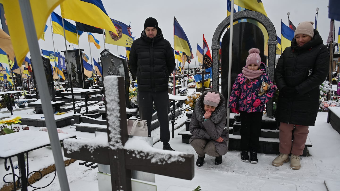 Family members mourned near the grave of a Ukrainian soldier on the Day of the Armed Forces of Ukraine at a cemetery in Kharkiv, on Dec. 6.