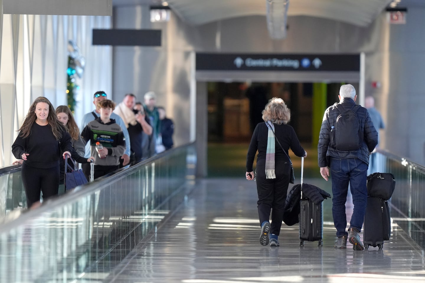 Travelers use a moving walkway and pull suitcases at Logan International Airport in Boston.