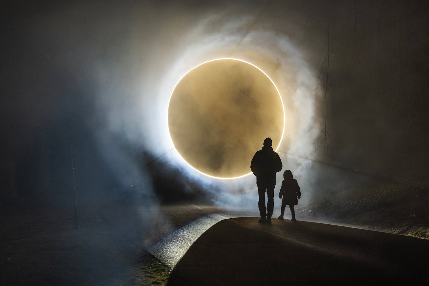 A man and child appear to be ready to be beamed up in "Eclipse," one of the installations created by MASARY at “SOLSTICE: Reflections on Winter Light” at the Mount Auburn Cemetery.