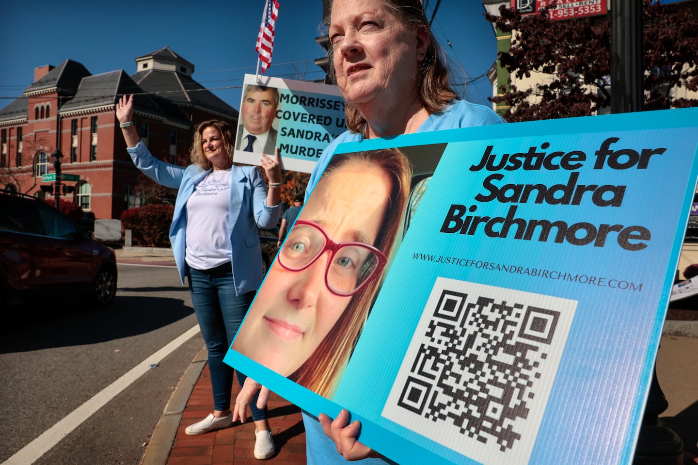 Patricia McCormack, left, and Barbara Wright, of Justice for Sandra Birchmore, held signs during a standout near town hall in Stoughton on Oct. 19. Wright said that Birchmore was a second cousin and good friend. “I wish it never happened. It’s so sad, she didn’t deserve this at all,” she said.