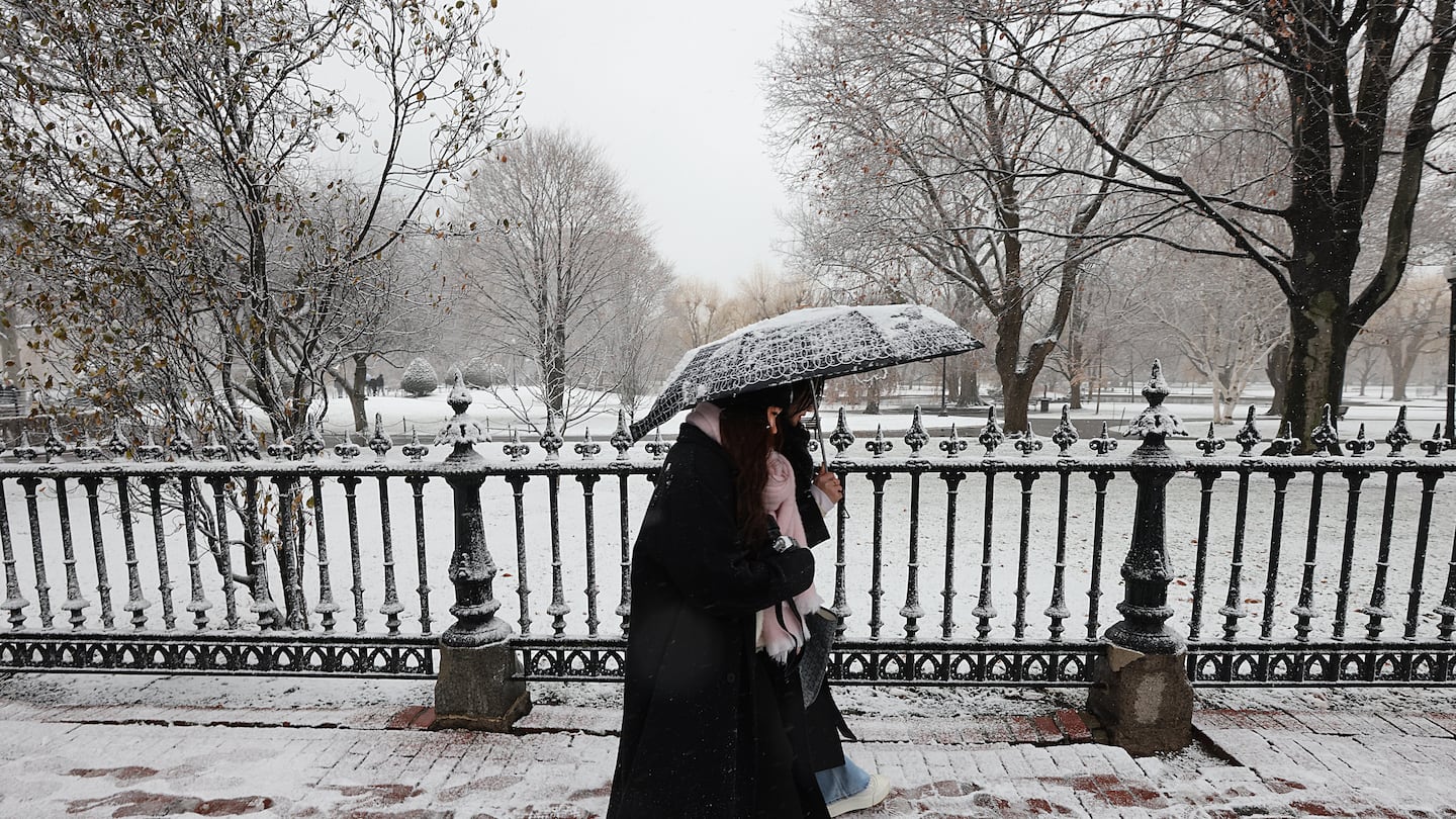 Two people shared an umbrella as they walked past a snowy Public Garden in Boston on Friday.